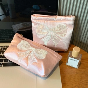 Détail de broderie nœuds blancs sur une trousse de maquillage en satin rose haute qualité