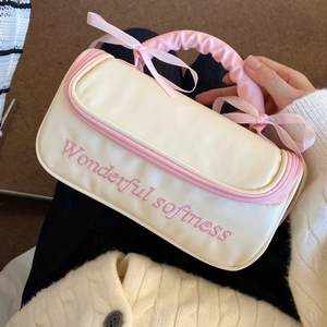 Détail de la trousse de maquillage avec poignée à nœud et broderie 'Wonderful softness'