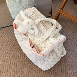 Cream floral quilted tote bag with top zipper and plush bunny charm for travel