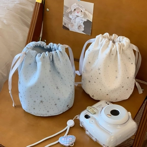 Detail of blue and beige drawstring pouches with silver stars on a wooden surface