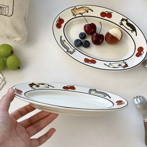 Détail d'une assiette en céramique avec motifs de chats et cerises peints à la main