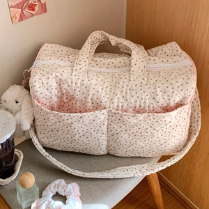 Close-up of floral quilted tote bag with pink piping and plush bunny charm on a stool