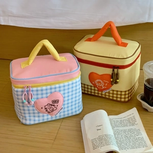 Close-up of blue and yellow checkered canvas lunch bags with heart embroidery on wood floor