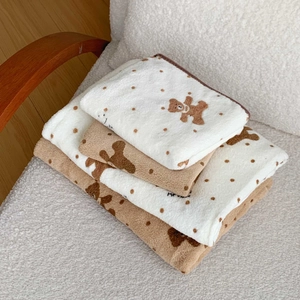 Polka dot bear coral fleece towel set folded on a cozy white boucle chair