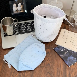 Star pattern drawstring cosmetic bags in white and light blue on a workspace desk