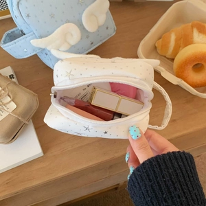 Detailansicht der Kosmetiktasche mit Sternstickerei und Plüschflügeln auf Holz