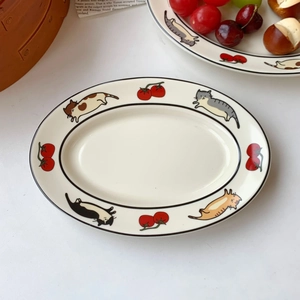 Détail d'une assiette ovale en céramique avec motifs de chats et tomates peints à la main