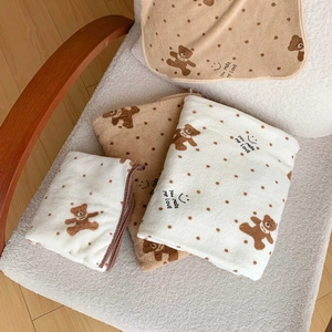 Close-up of soft coral fleece towel with cute bear pattern and polka dot texture