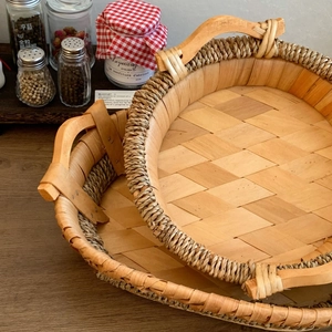 Detailed view of two-piece round woven wooden trays with handles in a rustic kitchen setting