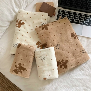 Detailed texture of thick coral fleece towels with polka dot bear embroidery on bed