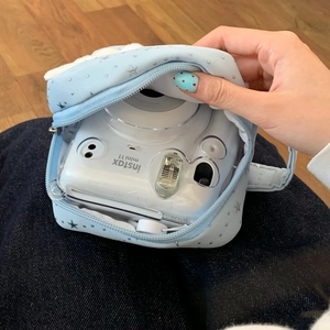 Nahaufnahme der blauen Sterntasche mit einer Instax Mini 11 Kamera in transparenter Hülle