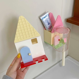 Dettaglio del portaspazzolino a forma di casa con bicchieri colorati e fessure porta