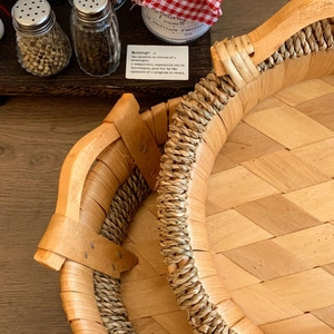 Close-up of handwoven wooden fruit basket with rustic rope trim and metal-fixed handle