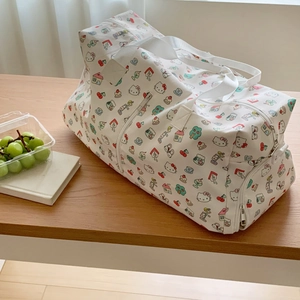 Detail of Hello Kitty travel bag with large capacity and cartoon prints on wooden bench