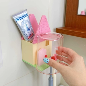 Dettaglio del portaspazzolino a forma di casa con tetto rosa e parete gialla chiara