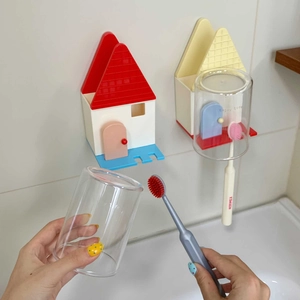 Dettaglio del portaspazzolino a parete a forma di casa con bicchiere capovolto drenante