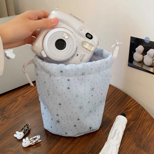 Close-up of putting a camera into the light blue drawstring pouch with star prints