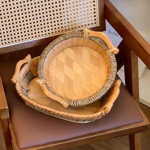 Close-up of hand-woven rattan trays with diagonal pattern and curved handles on a chair