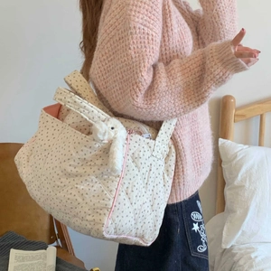 Detail of floral quilted tote bag with pink piping and cute bunny charm on shoulder