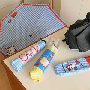 Detailed view of blue checkered umbrella with cartoon cat and apple print including storage pouch