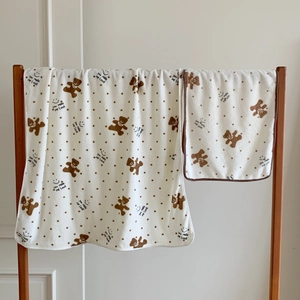 Detail of soft coral fleece towel set with cute bear pattern and polka dots on wood rack