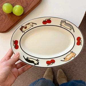 Détail d'une assiette ovale en céramique avec illustrations de chats mignons et de tomates