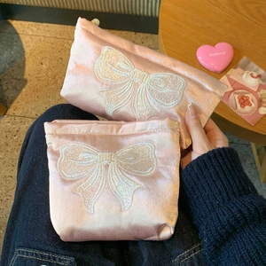 Détail de deux pochettes en satin rose avec broderie nœud blanc et fini nacré brillant