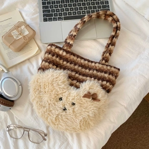 Detail of striped plush tote bag with a cute 3D bear decoration on white bedding