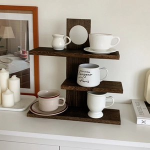 Close-up of a three-tier dark solid wood display shelf with elegant ceramic teacups