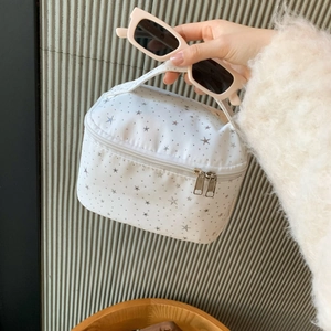 Detail view of white cosmetic bag with silver stars and sturdy zipper handle