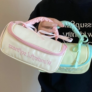 Gros plan du sac en satin avec nœud, broderie Wonderful Softness et poignée rembourrée