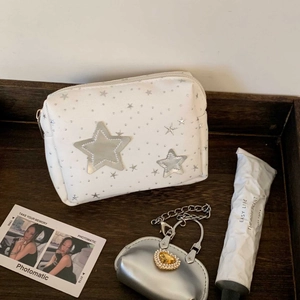 Detailed texture of white cosmetic bag with silver stars and heart-shaped metal charm