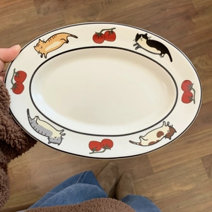 Détail d'une assiette ovale en céramique avec illustrations de chats et de tomates
