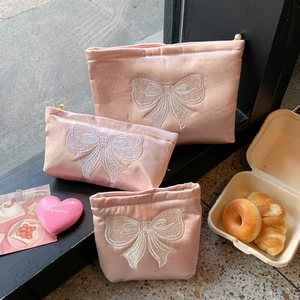 Lot de trois trousses de maquillage en satin rose avec nœuds brodés et perles de fermeture