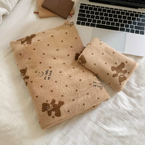 Close-up of plush laptop sleeve and pouch with bear polka dots on a textured bed sheet