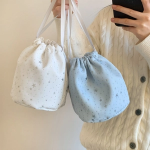 Detail of white and light blue drawstring bags with silver star patterns on fabric