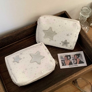 Detail of star-patterned makeup bags with blue star patches in a wooden tray