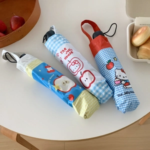 Detailed view of portable umbrellas with cartoon cat prints and apple patterns on table