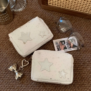Detail of white star cosmetic bag with silver star patches and metallic bow charm