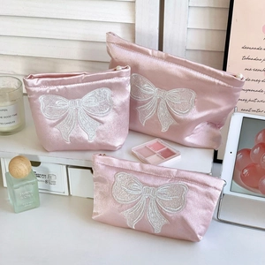 Lot de trois trousses à maquillage en satin rose avec nœuds brodés et perles de zip