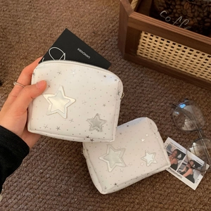 Detailed view of a white PU makeup bag featuring silver star prints and 3D star applique