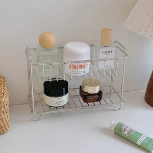 Detail of a two-tier stainless steel organizer shelf for cosmetics on a minimalist desk