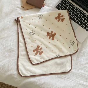 Close-up of soft coral fleece towel featuring cute bear dots and text on a white bed sheet
