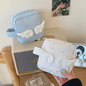 Kosmetiktasche mit Sternenprint und Plüschflügeln auf einem Vintage Lautsprecher