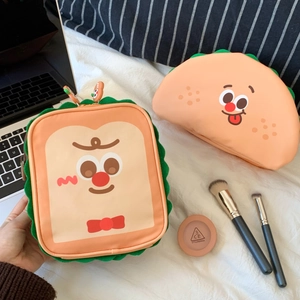 Cute toast and taco-shaped cosmetic bags with embroidered faces on a soft bed