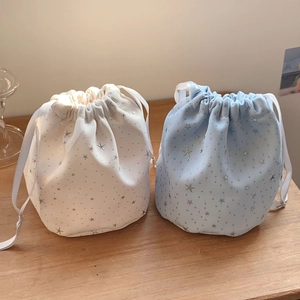 Detail of star pattern drawstring bags in pearl white and light blue cotton fabric
