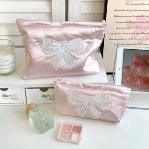 Détail des trousses de maquillage en satin rose avec broderie nœud élégante et zip perlé