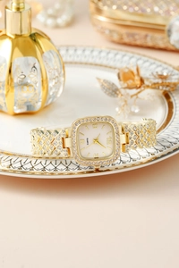 Dettaglio dell'orologio quadrato dorato con strass su un piatto decorativo