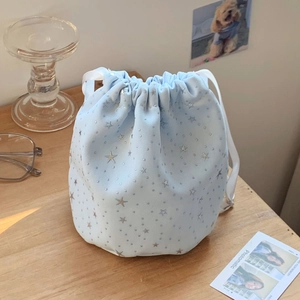 Detail of light blue drawstring pouch with silver star patterns on a wooden table