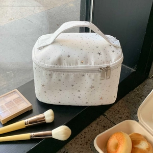 Detail of white star-patterned makeup bag showing sturdy handle and dual zippers
